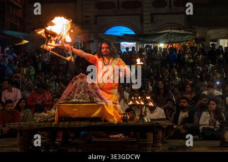In Dashashwamedh Ghat in Varanasi führt ein Priester das Aarti-Ritual durch, indem er eine brennende Lampe schwenkt, während die Zuschauer das spirituelle Ereignis beobachten. Stockfoto