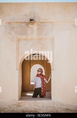 Kaukasische Frau mit Hijab steht im Fenster des Forts, Oman Stockfoto