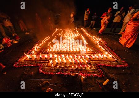Ein großer Blick auf ein großes geometrisches Feuer Rangoli aus brennenden Lampen in Raja Ghat in Varanasi, umgeben von Schaulustigen im Dunkeln. Stockfoto