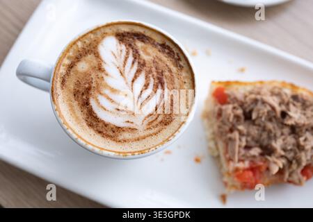 Köstliches Frühstück mit einem Cappuccino mit Latte Art und einem Toast mit Tomaten und Thunfisch Stockfoto