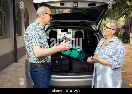 Ältere Menschen verbringen einen lustigen Moment beim Verladen des Kofferraums mit Taschen für eine Autofahrt im Urlaub. Paare genießen ihre Liebe zum gemeinsamen Reisen, Freizeitziele in der Freizeit. Stockfoto