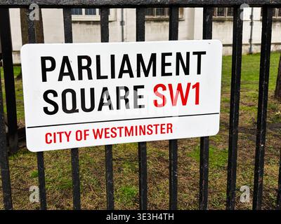 Weißes Straßenschild mit der Aufschrift Parliament Square SW1 auf Eisengeländern an der historischen Westminster Church in London Stockfoto