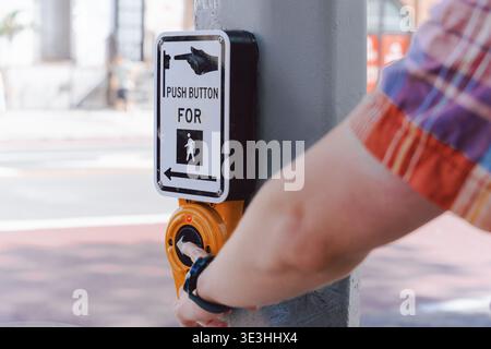 Handbetätigung des Fußgängerschalters am Straßenmast, Aktivierung des Gehsignals, Stadtsicherheit, Transportsystem Stockfoto