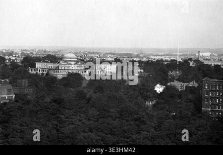 Dieses Schwarz-weiß-Luftbild, wahrscheinlich aus den 1920er oder 1930er Jahren von Angelo Rizzuto, bietet einen Panoramablick auf das Bronx Community College (damals wahrscheinlich der Campus der University Heights der New York University), das sich auf einem Hügel in der Bronx, New York, befindet. Die neoklassizistischen Gebäude, einschließlich der gewölbten Gould Memorial Library, sind unter den üppigen Baumbedeckungen hervorzuheben, wobei das breitere Stadtbild in der Ferne unter einem trüben Himmel sichtbar ist. Es bietet einen Einblick in die architektonische und städtische Entwicklung New Yorks während dieser Zeit. Stockfoto