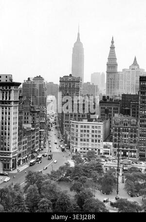 Dieses Schwarz-weiß-Foto von Angelo Rizzuto, wahrscheinlich aus den 1950er Jahren, bietet einen erhöhten Blick auf den Broadway in New York City, der vom Union Square nach Norden in Richtung Madison Square blickt, mit dem Empire State Building und dem Metropolitan Life Tower in der unverschämten Entfernung. Die belebte Straße ist gesäumt von historischen Gebäuden, in denen Oldtimer und das tägliche Leben in einer vergangenen Zeit der Stadt zu sehen sind. Stockfoto