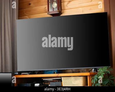 Großer Flachbildfernseher an Holzwand im modernen Wohnzimmer. Display mit leerem schwarzen Bildschirm des Modells. Konzept des Home Entertainment Systems Stockfoto