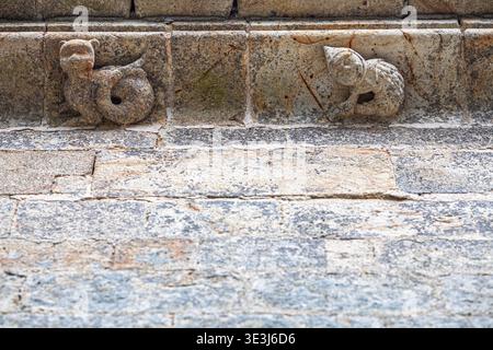 Detaillierte Steinschnitzereien fantastischer Tiere zieren das Gesims der historischen Dreifaltigkeitskapelle in Plumergat, Bretagne, Frankreich. Mittelalterliche Architektur. Stockfoto