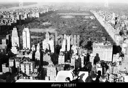 Dieses atemberaubende Schwarzweiß-Luftbild von Angelo Rizzuto, wahrscheinlich aus den 1940er Jahren, zeigt einen weiten Blick auf Manhattan und blickt nach Norden in Richtung Central Park. Die Zuschauer blicken auf die berühmte Stadtlandschaft mit ihren hoch aufragenden Gebäuden und die grüne Weite des Parks. Die Szene bietet einen Einblick in die alte New Yorker Architektur und das urbane Leben. Stockfoto