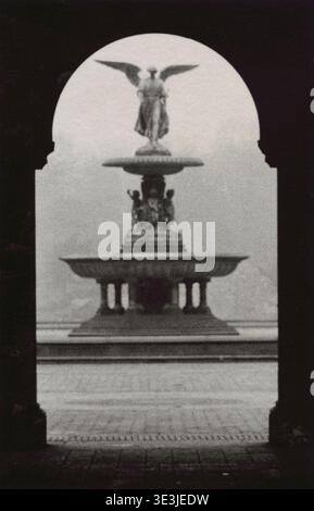 Dieses Vintage-Foto von Angelo Rizzuto aus den 1950er Jahren zeigt die berühmte Angel of the Waters Statue auf dem Bethesda Fountain im Central Park, New York City. Die Szene ist dramatisch durch einen Bogengang eingerahmt und bietet einen weichen, körnigen und etwas ätherischen Blick auf das historische Wahrzeichen. Stockfoto