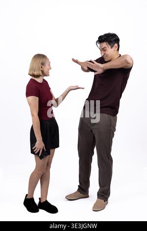 Eine junge Frau, die einen Mann beschuldigt, der in einem Studio verwirrt aussieht Stockfoto