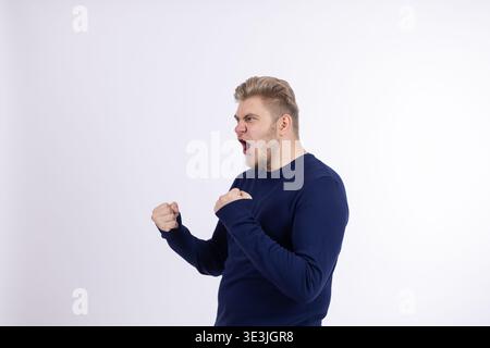 Ein wütender Mann, der im Studio mit Fäusten brüllt Stockfoto