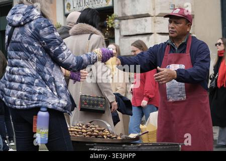 Geröstete Kastanienhändler, der Touristen in Piazza Navona, Rom, Italien serviert. Winterliche Street Food-Tradition, Leute versammelten sich, um warme Snacks zu kaufen. Stockfoto