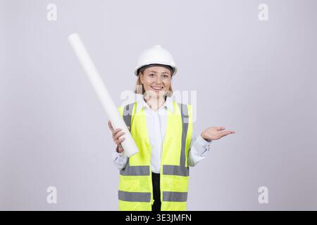Frau in Sicherheitsweste, die einen Plan auf weißem Hintergrund hält Stockfoto