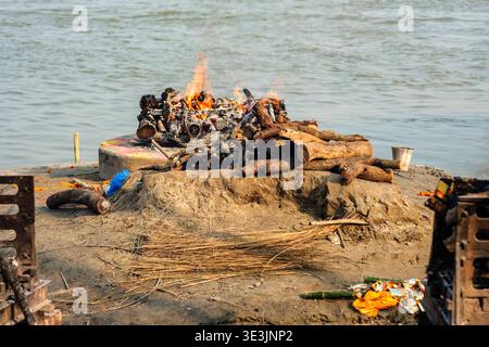 Am Ufer des Ganges bei Lali Ghat in Varanasi brennt ein Trauerhaufen, in dem Feuerholz für traditionelle Einäscherungszeremonien zubereitet wird. Varan Stockfoto