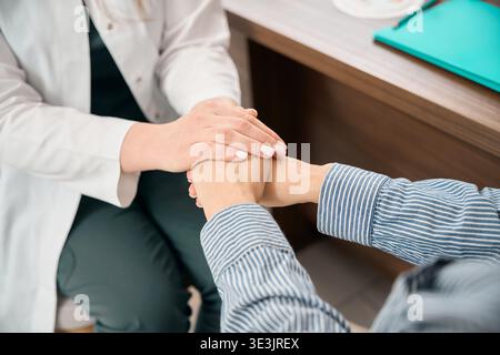 Mitfühlende Ärztinnen, die Patienten in der Arztpraxis trösten Stockfoto