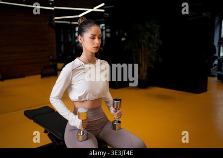 Frau, die mit Kurzhanteln im modernen Fitnessstudio trainiert Stockfoto