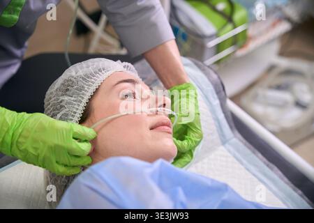 Ruhige Patientin mit Sauerstoffkanüle in der medizinischen Einrichtung Stockfoto