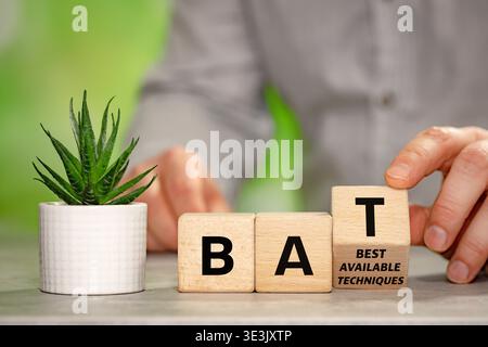 Der Geschäftsmann dreht einen Holzblock mit dem Symbol BAT, beste verfügbare Techniken. Ein Geschäftskonzept, das sich auf die Umwelt bezieht. Moderne Produkte Stockfoto
