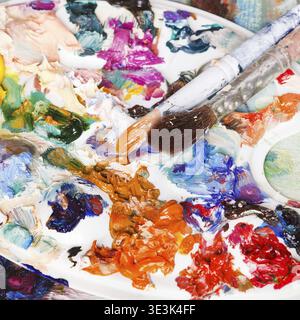 Gebrauchte Kunstpalette mit Ölfarben und zwei Pinseln Stockfoto