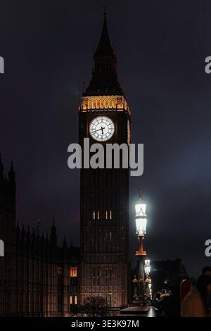 Blick auf den berühmten Big Ben Uhrenturm, der die dunkle Londoner Nacht durchquert, und sein beleuchtetes Gesicht ein Leuchtfeuer vor dem schattigen Himmel, London, England, United Stockfoto