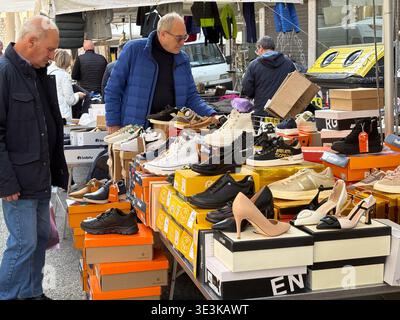 Porta Portese Flohmarkt, Rom, Italien. Käufer untersuchen verschiedene Schuhstile, darunter Sneakers und Absatzschuhe, die draußen auf Boxen ausgestellt sind. Stockfoto