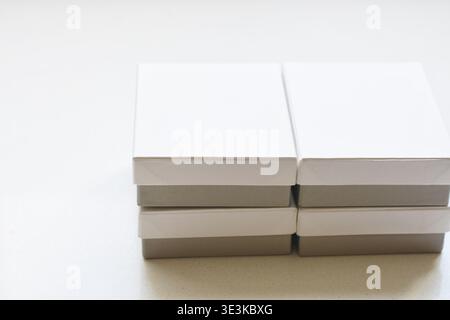 Hochauflösendes Bild von weißen quadratischen Feldern mit grauen Untergründen, die ordentlich auf einem weißen Tisch angeordnet sind. Minimalistische Zusammensetzung für Verpackung, Branding, Stockfoto