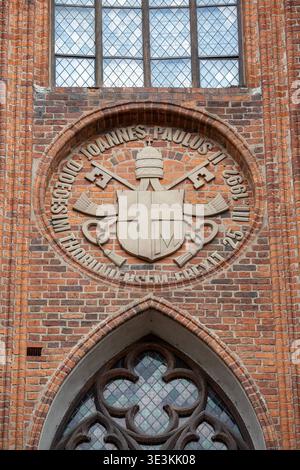 Torun, Polen - 27. Juni 2020: Päpstliches Wappen Johannes Paul II. Auf der roten Ziegelfassade der gotischen Kathedrale von Torun Stockfoto