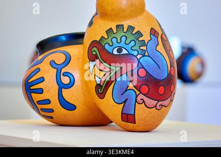 Nahaufnahme zweier lebendiger handgefertigter Keramikgefäße auf einer hellen Holzoberfläche. Im Vordergrund befindet sich eine Kürbisvase mit einer schmalen Vase Stockfoto
