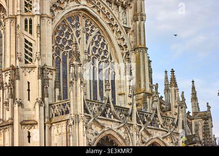 Nahaufnahme der gotischen Kathedralarchitektur mit komplizierten Steinschnitzereien, Spitzbögen und aufwendigen Gewändern auf einem großen Buntglas Stockfoto