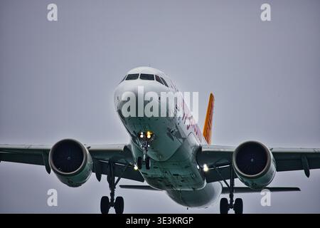 Eine professionelle Tele-Aufnahme eines kommerziellen Jets bei Endanflug. Das Bild erfasst das Flugzeug aus einem niedrigen Winkel und zeigt das verlängerte Fahrwerk. Stockfoto