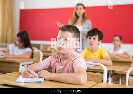 Fleißiger Jugendlicher, der mit Klassenkameraden in der Schule studiert Stockfoto