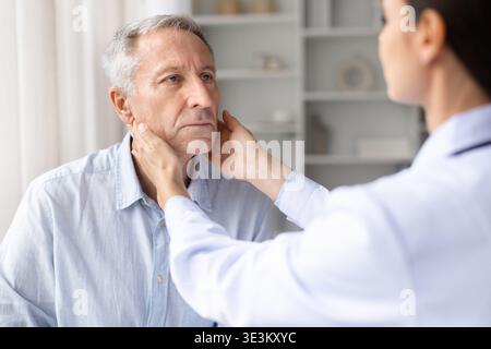 Weibliche Ärztin, die Lymphknoten berührt und Seniorin in der Klinik aufgesucht Stockfoto