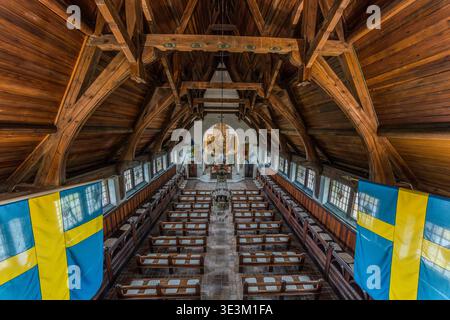 Blick auf das Schiff der Gustav-Adolf-Gedächtniskapelle in Lützen von der Galerie aus: Ein markantes hölzernes Tonnengewölbe in Form eines Schiffskiels, Bänke und der Altar im Hintergrund; schwedische Nationalflaggen auf beiden Seiten. Lützen, Sachsen-Anhalt, Deutschland Stockfoto