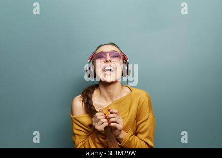 Musikgenuss-Konzept. Hübsche Frau, die Kopfhörer trägt. Ich schaue auf und lächelte. Lässiges Outfit. Porträt, das Emotionen und Stimmung hervorhebt. Modernes Leben Stockfoto