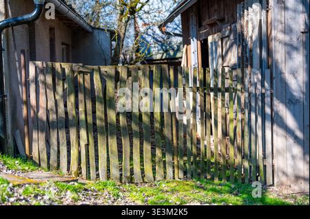 Altes hölzernes Gartentor zwischen ländlichen Gebäuden, rustikaler Eingang, der Grenzen, Privatsphäre und Schutz symbolisiert, ländlicher Lebensstil und traditionelles li Stockfoto