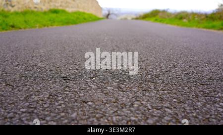 Nahaufnahme der Asphaltstraßenstruktur mit Bokeh-Hintergrund und Perspektive der führenden Linie Stockfoto