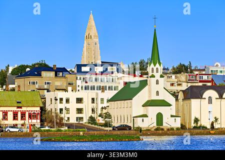 Die lutherische Freikirche steht am Tjornin See mit Halgrimskirkja im Hintergrund an einem sonnigen Tag in Reykjavik, Island. Stockfoto