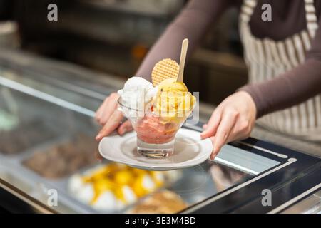 Hände halten den Teller mit drei Kugeln Eis Stockfoto
