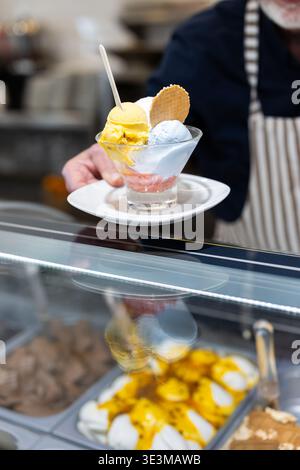 Hände halten den Teller mit drei Kugeln Eis Stockfoto
