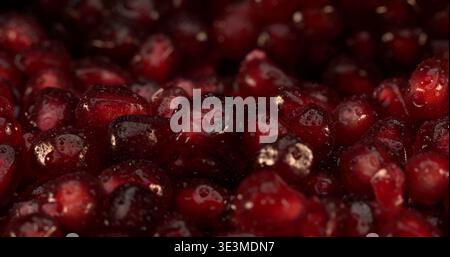 Frische rote Granatapfelkerne mit Wassertropfen auf dunklem Hintergrund auf einem Obstmarkt Stockfoto