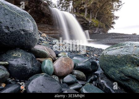 Bunte Steine und Wasserfall am Sandcut Beach - Jordan River Regional Park - in der Nähe von Sooke, Vancouver Island, British Columbia, Kanada Stockfoto