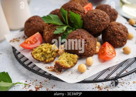 Stehen Sie mit köstlichen Falafelbällchen, Kichererbsen und Tomaten auf hellem Hintergrund, Nahaufnahme Stockfoto