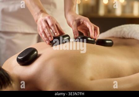 Hot-Stone-Massagetherapie im Spa mit Basaltsteinen auf dem Rücken Stockfoto