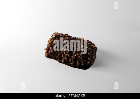 Süßigkeiten in Schokoladenglasur mit Nüssen und Puffreis. Nahaufnahme auf weißem Hintergrund. Stockfoto
