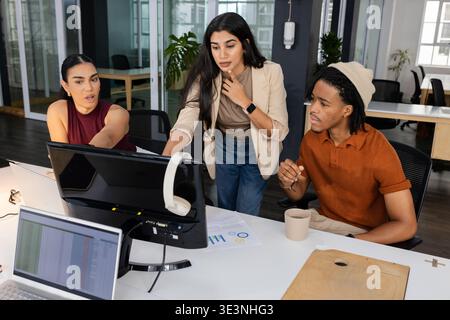 Verschiedene Kollegen arbeiten am Schreibtisch im Büro mit Monitoren, Diagrammen und Kaffeetassen zusammen Stockfoto