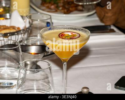 Passionsfrucht-Cocktail, serviert in einem Martini-Glas auf dem Restauranttisch, mit frischen Garnituren und eleganter Präsentation. Stockfoto