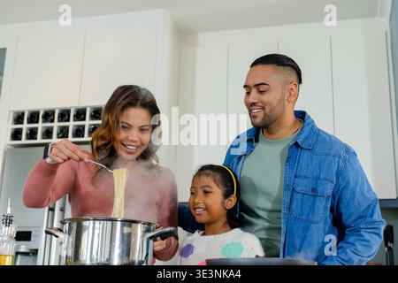 Dampfende Spaghettinudeln in heller, moderner Küche mit Stahltopf auf dem Herd Stockfoto