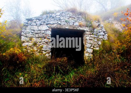 Die Ruine von Bauernhaus aus Stein im November Nebel auf dem Weg zum Monte Pau eingehüllt in Cogollo del Cengio in der Provinz Vicenza, Venetien, Italien. Stockfoto