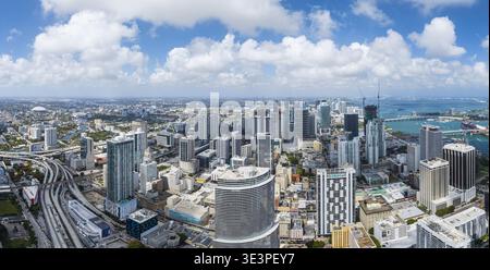Aus der Vogelperspektive sehen Sie die pulsierende Stadtlandschaft, wo glänzende Wolkenkratzer auf die gewundenen Straßen unter sich treffen und den hellen Himmel über Brickell, Miami, spiegeln Stockfoto