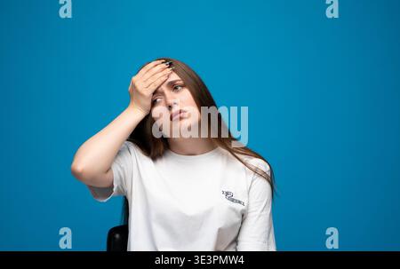 Junge Frau, die an Kopfschmerzen oder Migräne leidet, Schmerzen, Stress oder Fieber spürt und ihre Stirn berührt Stockfoto